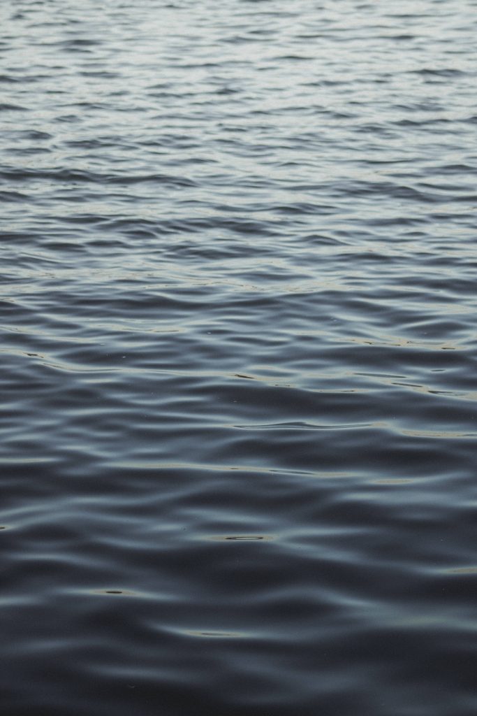 Minimalist dark blue water iPhone wallpaper with calm rolling ripples and deep navy tones