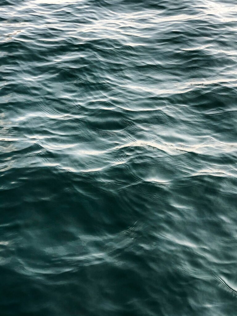 Serene deep blue water with gentle waves and soft natural glare realistic sea wallpaper background
