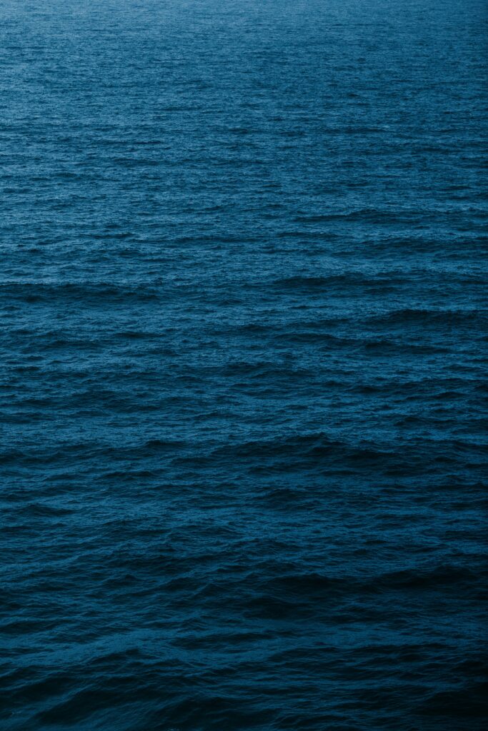 Calm deep blue water with gentle waves ripples minimalistic serene wallpaper background