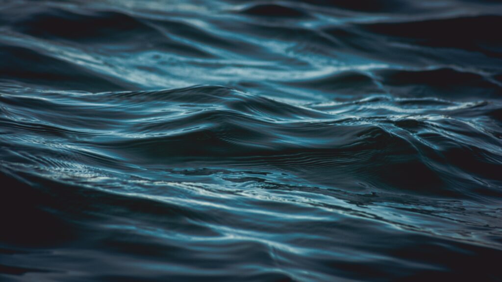 Deep blue water wallpaper with gentle waves reflections creating a calming aquatic background