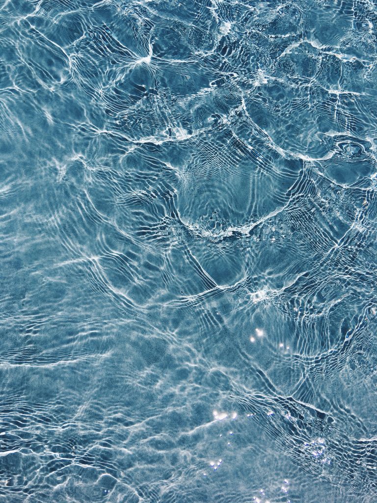 Crystal-clear water ripples with sunlight dancing on deep blue pool bottom iPhone wallpaper