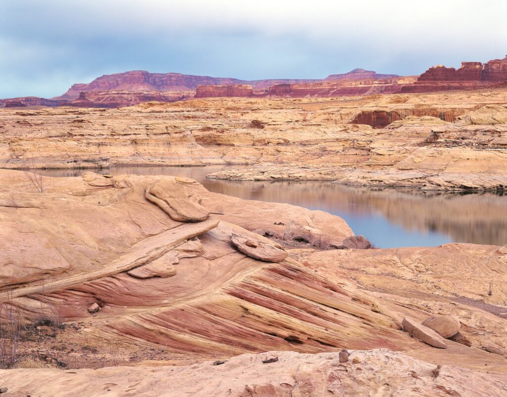 Desert canyon landscape wallpaper with rugged stones calm reflective coastal water serene earth tones