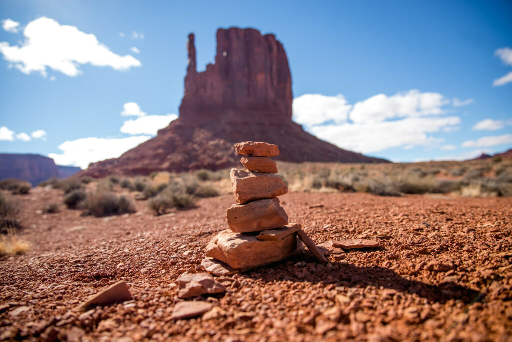 Balanced stone stack in serene desert canyon with red rocks and bright blue sky background Wallpaper