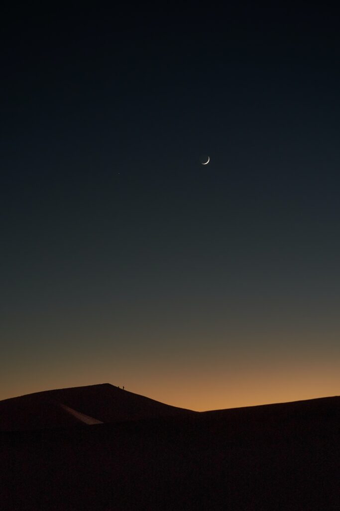 Serene evening desert landscape with rolling dunes crescent moon warm cool gradients wallpaper