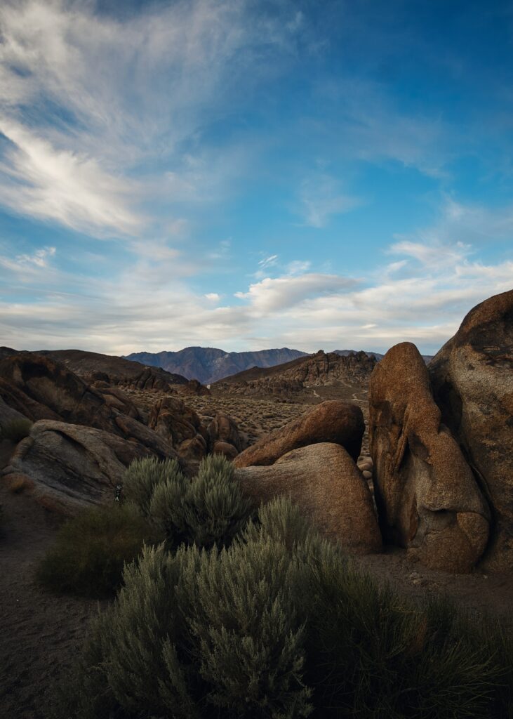 Dramatic desert landscape with rugged mountains soft clouds and weathered rocky terrain wallpaper
