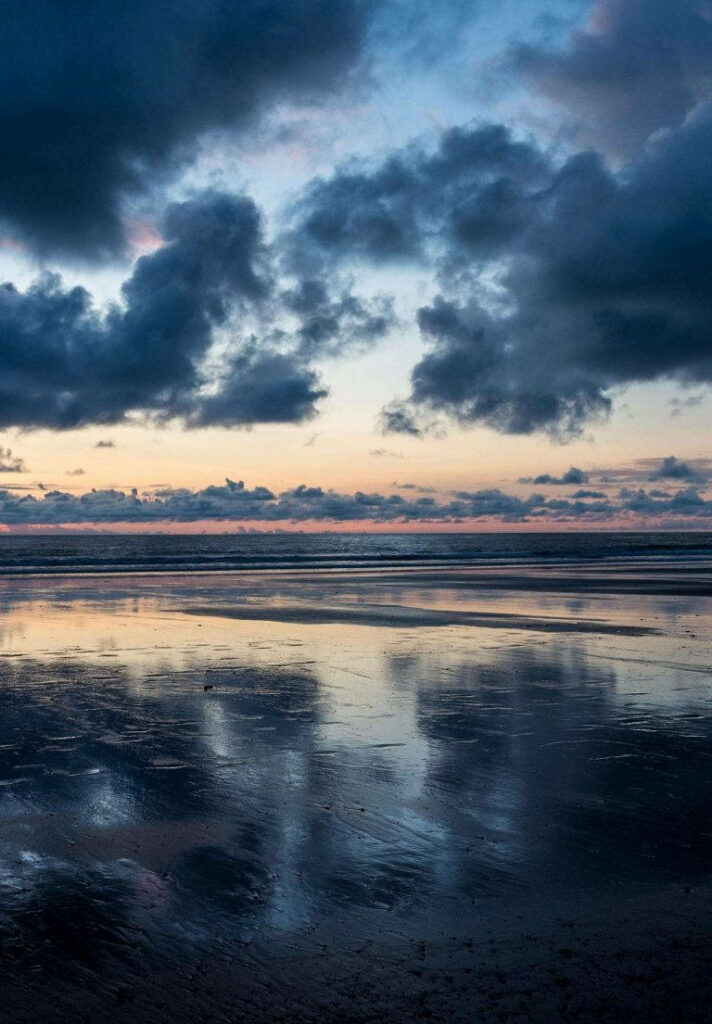 Moody Beach Scene: Reflective Wet Sand & Dramatic Twilight Sky Wallpaper