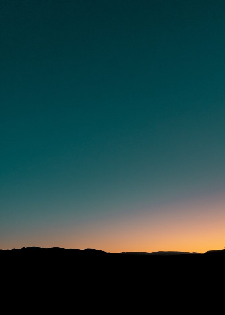 Serene dusk wallpaper with dark teal to golden gradient sky over silhouetted natural horizon