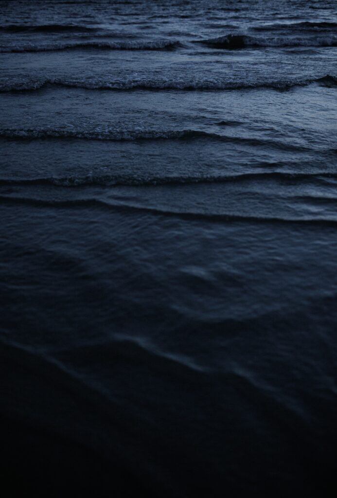 Serene water surface at dusk with gentle ripples and deep blue waves minimalist wallpaper background