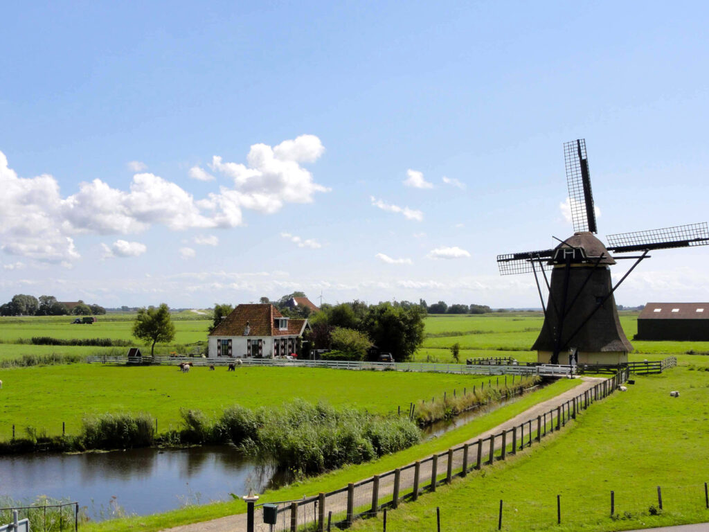 Idyllic Dutch Windmills: Lush Fields & Calm Waterway Wallpaper