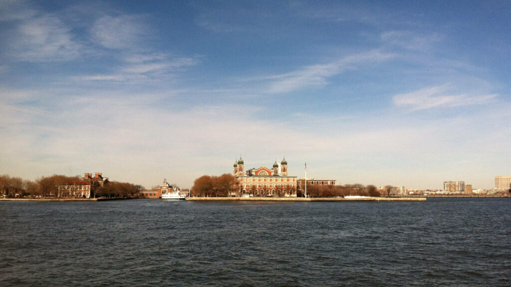 Serene Ellis Island View: Iconic Architecture & Natural Beauty Wallpaper