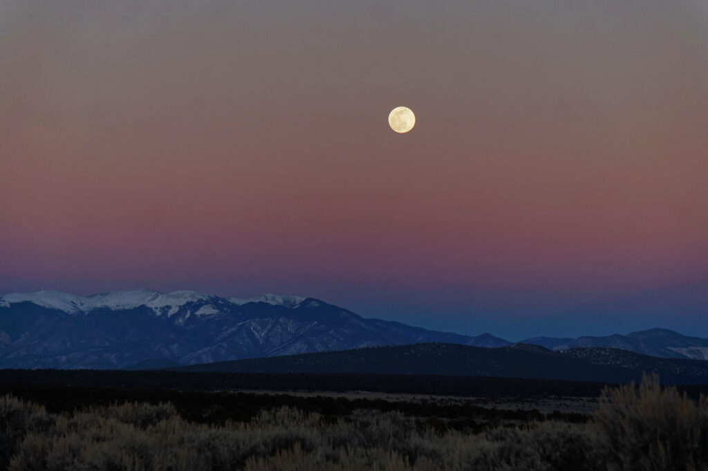 Glowing full moon over snowy mountains with twilight sky and peaceful field wallpaper background