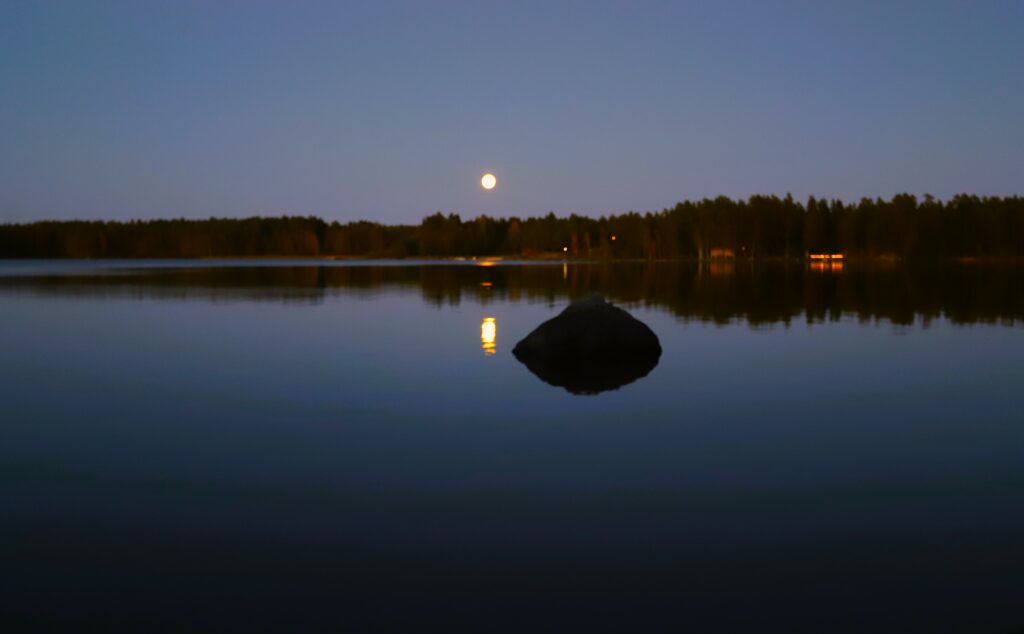 Serene evening lake with full moon reflection surrounded by dense forest peaceful nature scene Wallpaper
