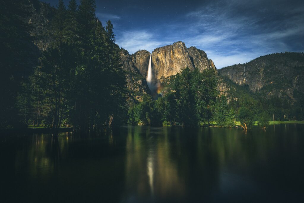 Serene evening mountain landscape with calm lake reflection lush trees and twilight starry sky background Wallpaper