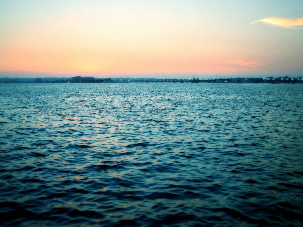 Serene evening sea wallpaper with calm ripples pastel blue and orange sky at dusk background
