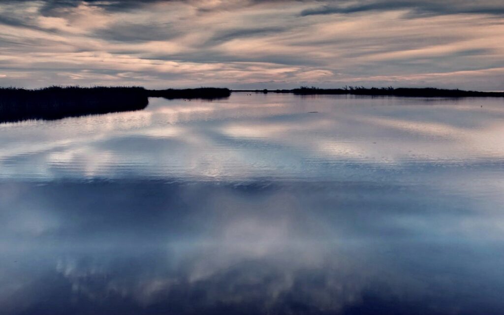 Serene evening wallpaper with calm water reflecting soft blue and pink clouds for relaxation