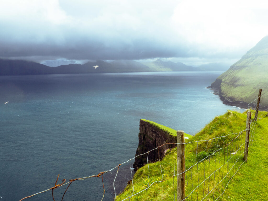 Serene Faroe Islands Coastal Wallpaper: Lush Cliffs & Calm Sea