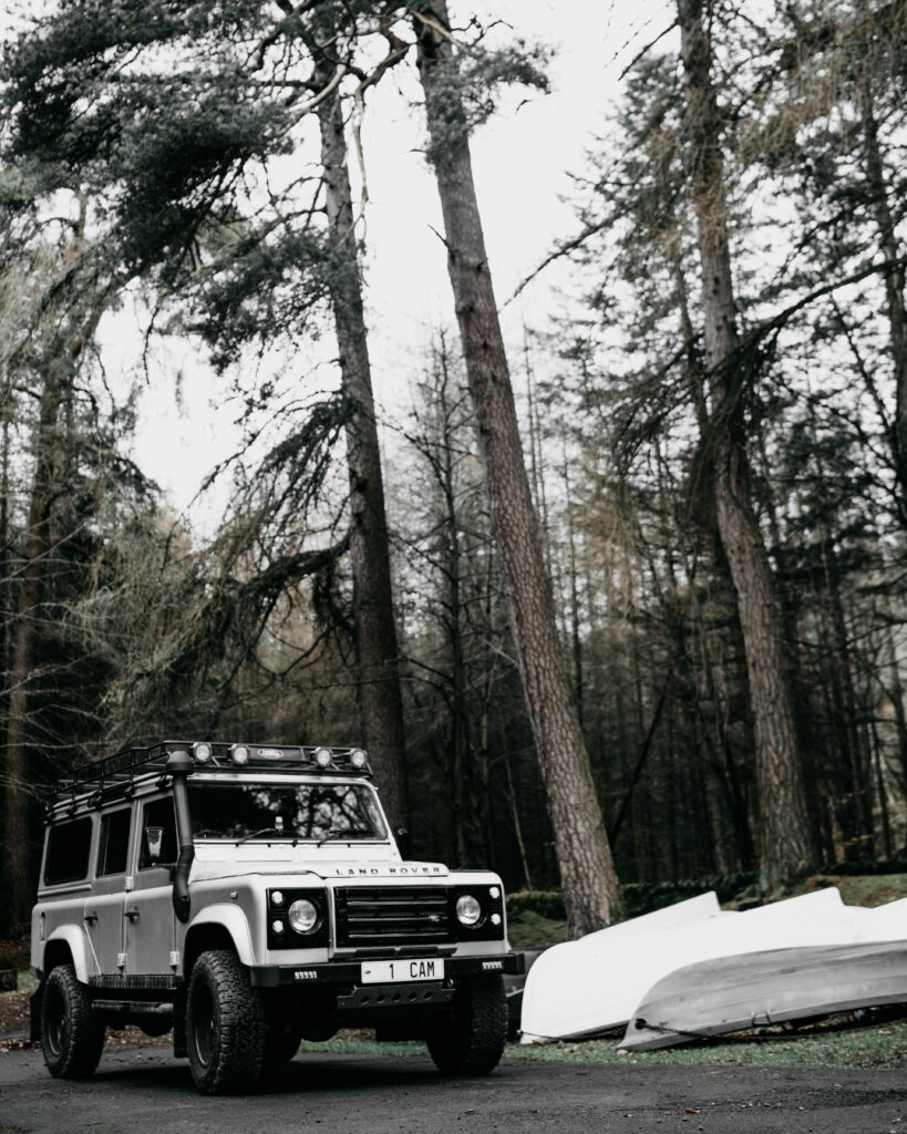 White Land Rover Defender in Serene Forest - Nature Adventure Background Wallpaper