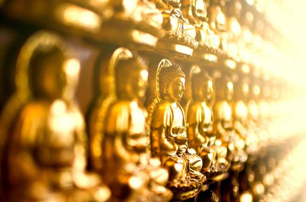Golden Buddha statues in a row with glowing bokeh for a calming spiritual wallpaper background