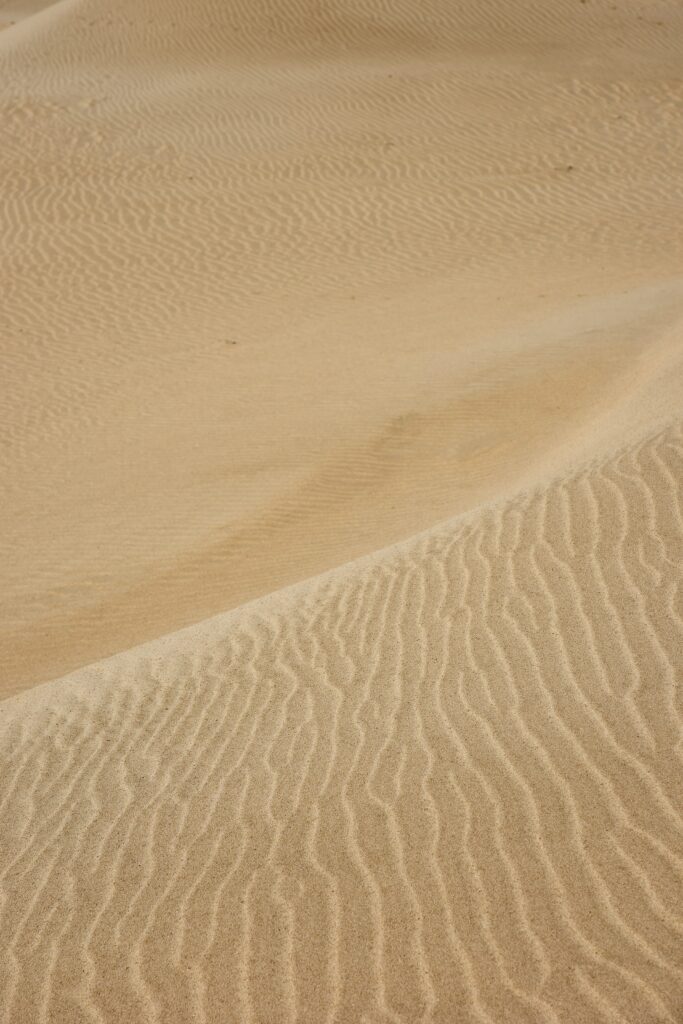 Tranquil desert wallpaper with golden sand dunes and rhythmic wind patterns in sunlight