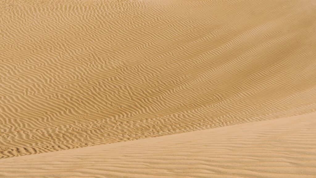 Serene desert wallpaper with golden sand dunes and intricate wavy wind patterns minimalist textures