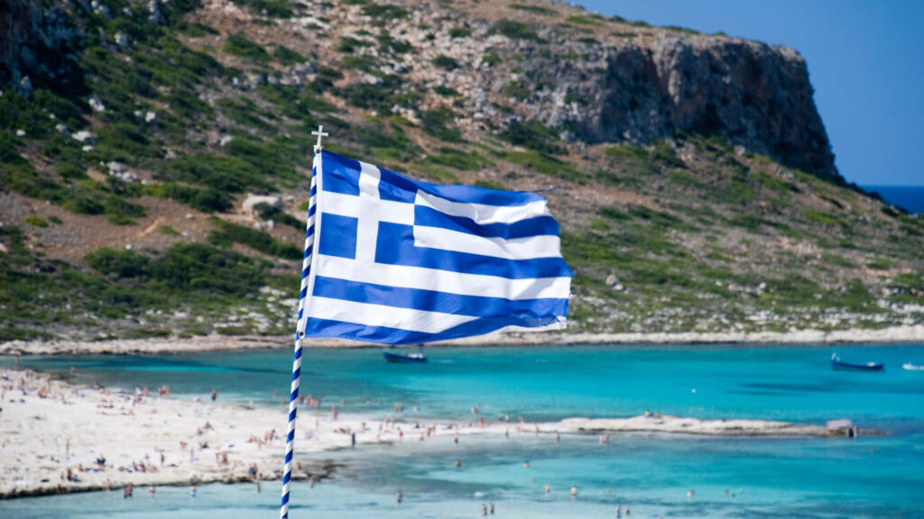 Serene Greece Wallpaper: Blue & White Flag over Turquoise Beach