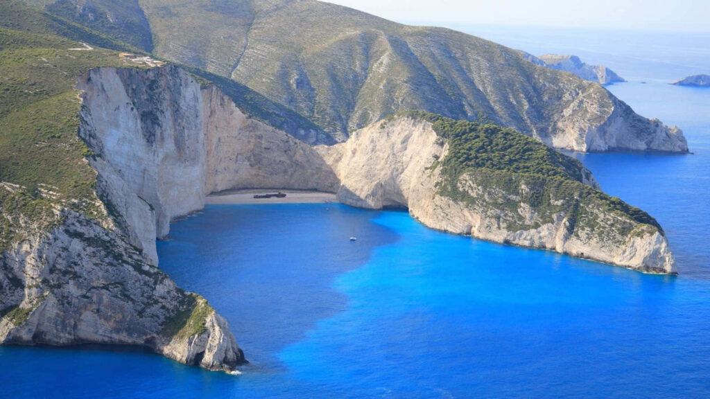 Serene Greek Beach Wallpaper: Turquoise Waters & Dramatic Cliffs