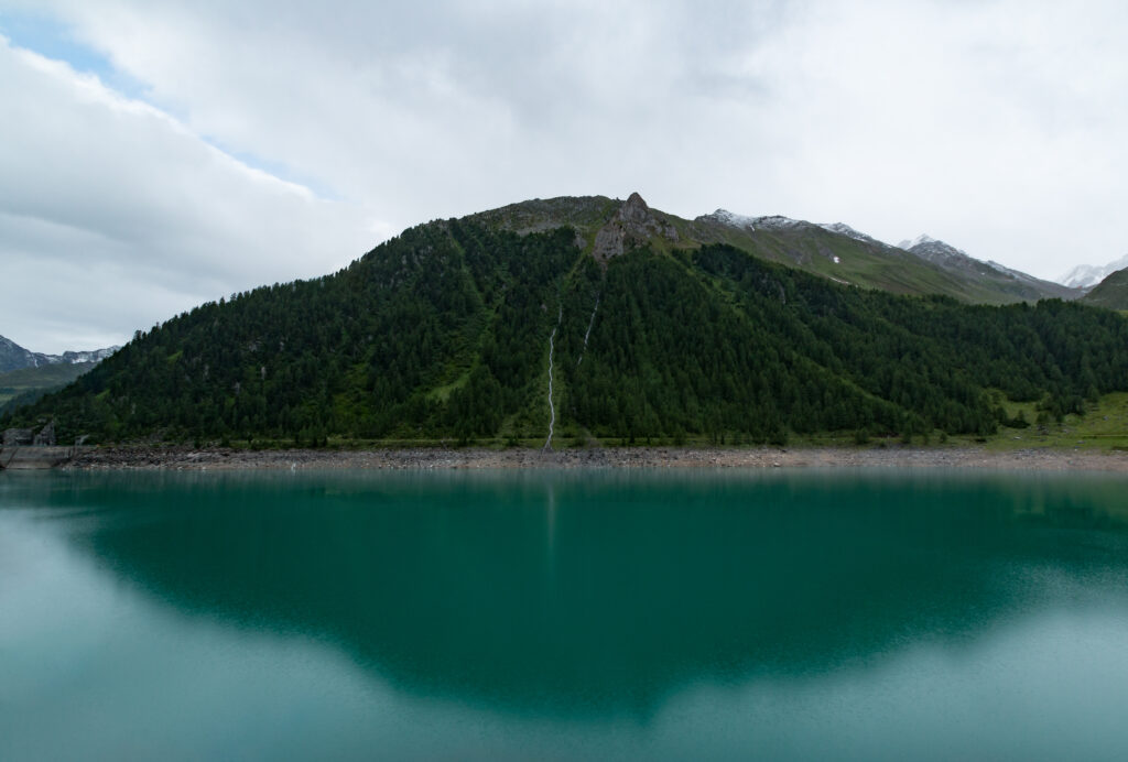 Serene green mountain reflected in calm turquoise lake under soft overcast sky peaceful nature wallpaper