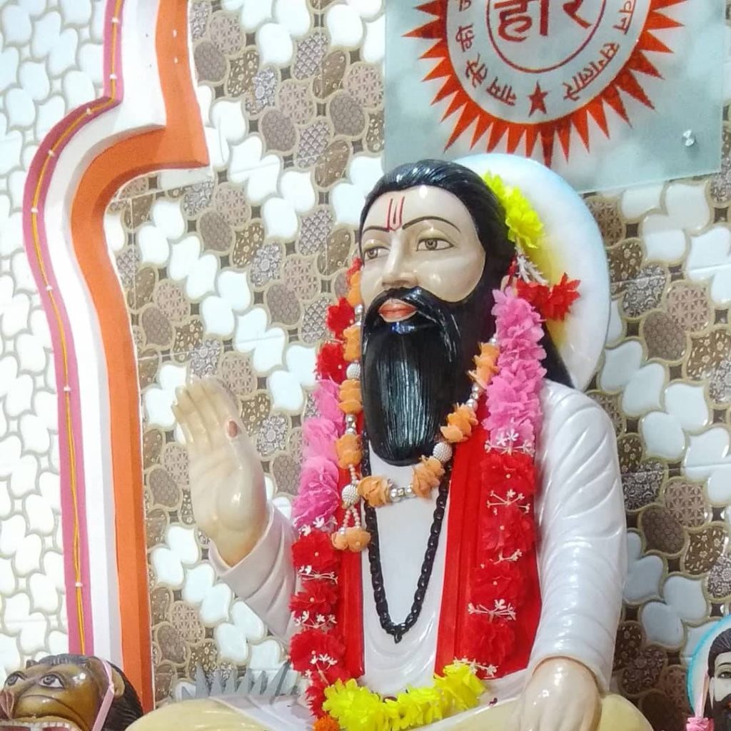 Guru Ravidas statue wallpaper with vibrant garlands and ornate geometric spiritual backdrop
