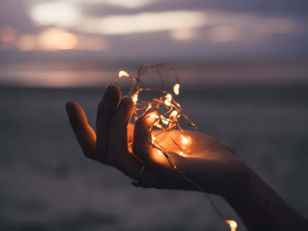 Tranquil Hand Holding Glowing Fairy Lights on Soft Focus Background Wallpaper