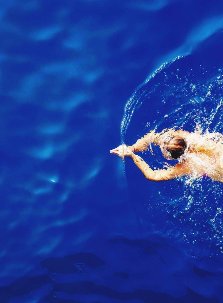 High-angle view of swimmer gliding through vibrant blue water with dynamic splashes serene scene Wallpaper