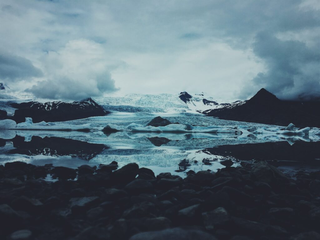 Icy landscape wallpaper with floating snow-capped icebergs rugged stones reflective waters