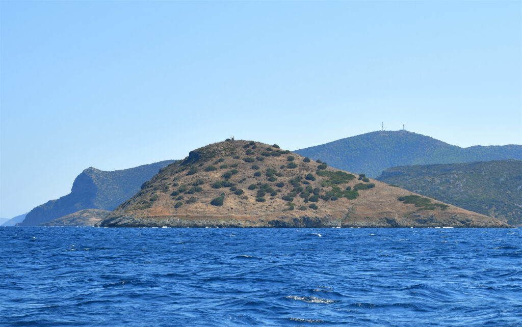 Serene island with rugged terrain and sparse vegetation by deep blue sea under bright sky wallpaper