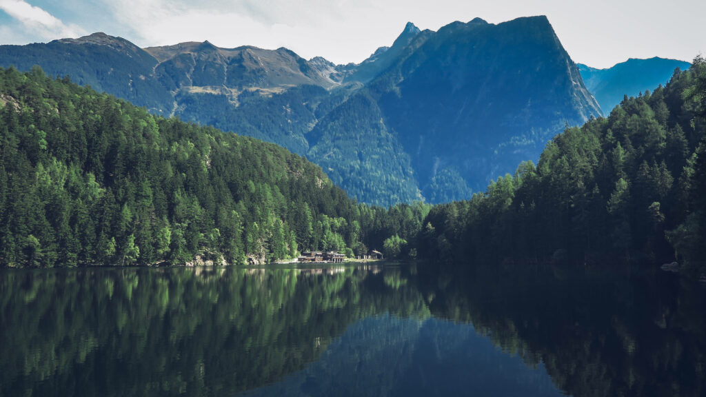 Lake Gosausee Austria crystal-clear waters reflecting green forests and majestic mountain peaks Wallpaper