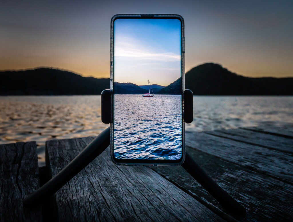 Serene Lake Sunset Wallpaper with Boat & Smartphone Photography