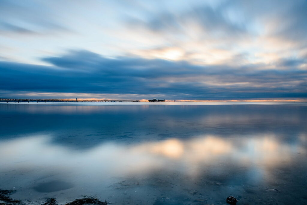 Serene Lakeside HD Wallpaper: Calm Waters & Soft Sky Hues