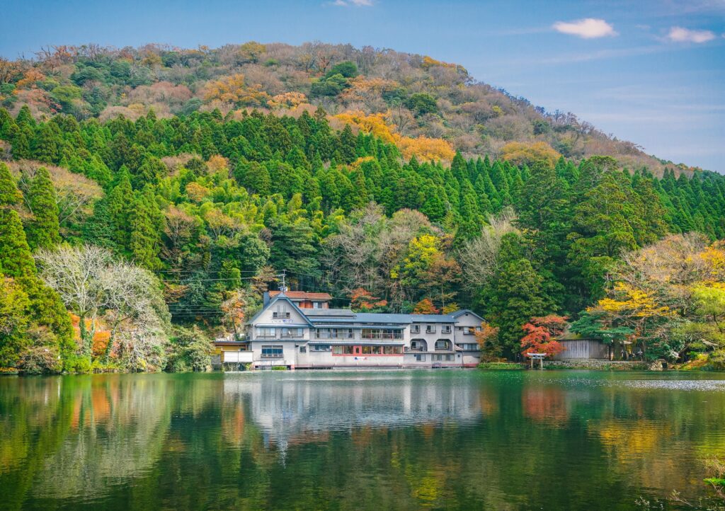 Serene lakeside with traditional building amid green autumn trees reflecting calm water HDR scenery Wallpaper