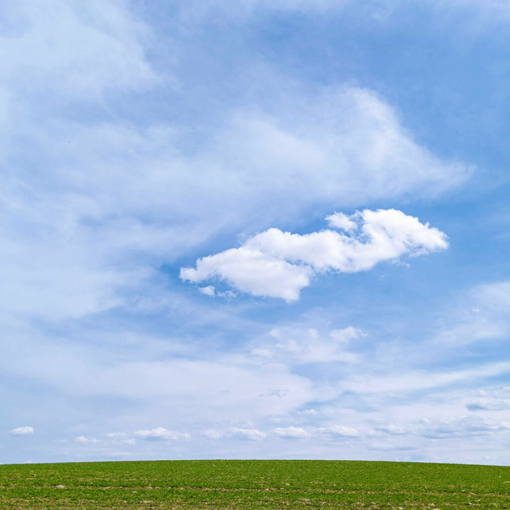 Serene Landscape Wallpaper: Tranquil Green Field & Cloudy Sky