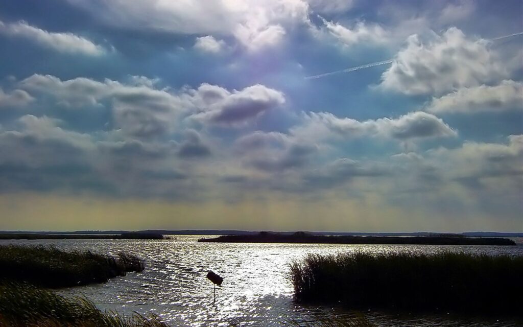 Serene landscape wallpaper with dramatic sky soft clouds shimmering sunlight gentle water ripples