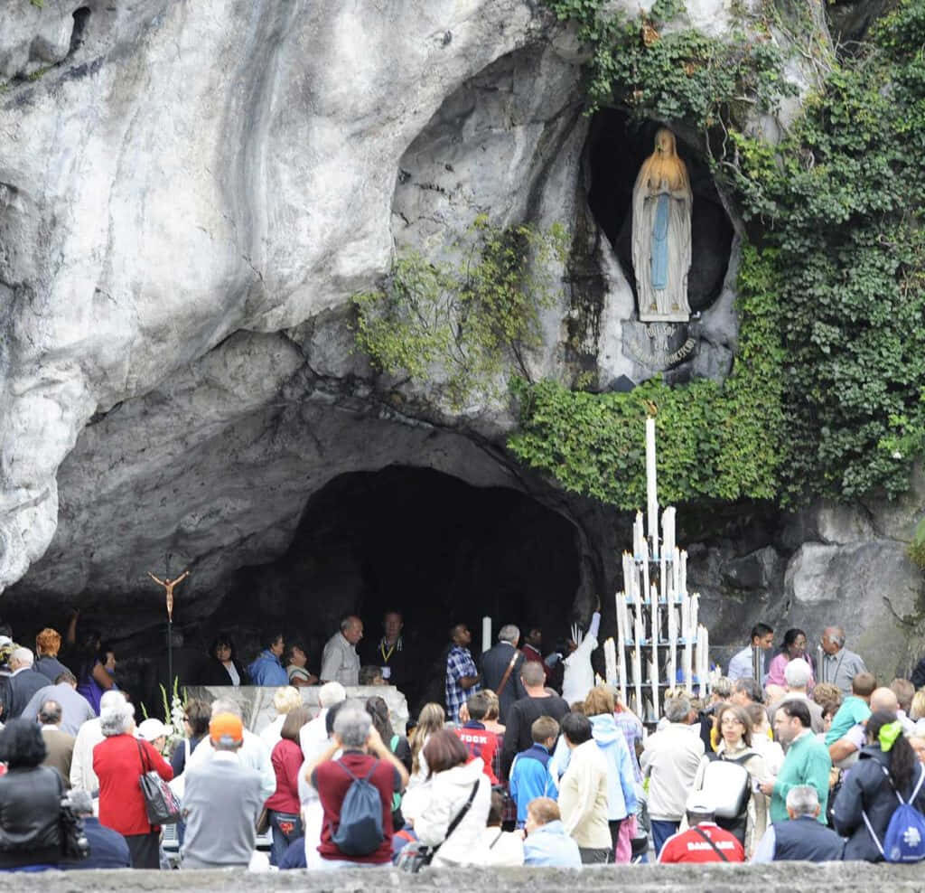 Serene Lourdes Grotto: Pilgrims & Natural Beauty Wallpaper Background