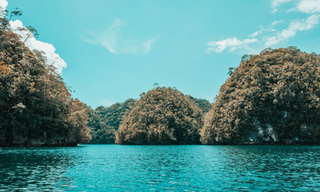Lush green islands above calm turquoise water with bright sky serene natural coastal wallpaper