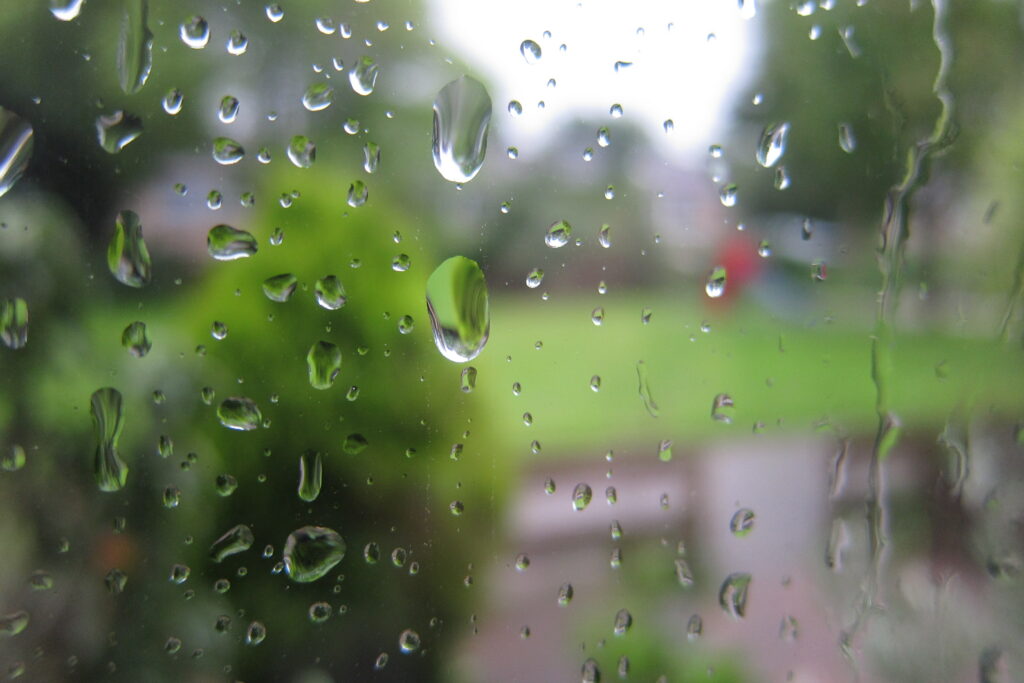 Serene Macro of Raindrops on Glass with Blurred Green Background Wallpaper
