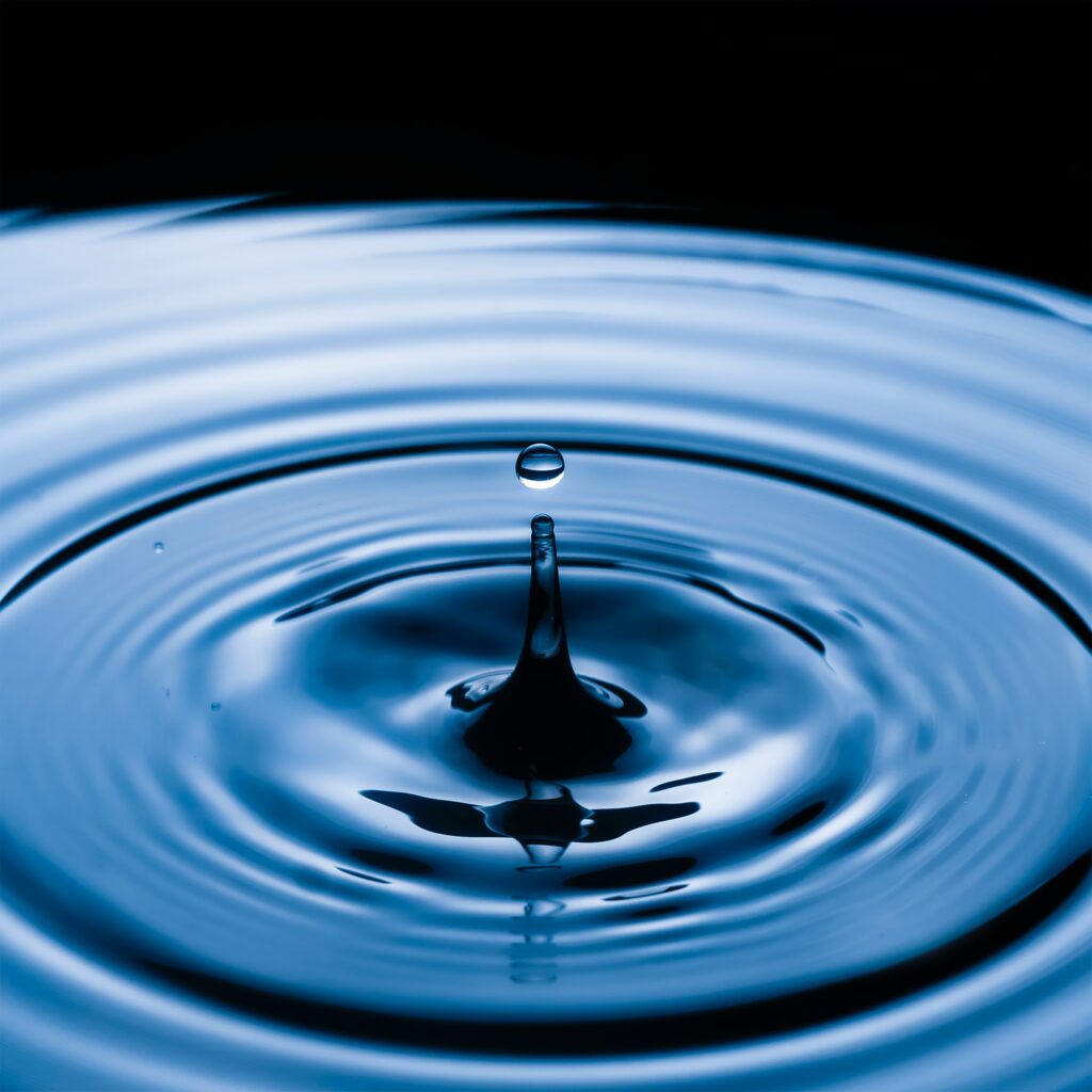 Serene Macro: Water Droplet Ripples on Calm Blue Surface Wallpaper