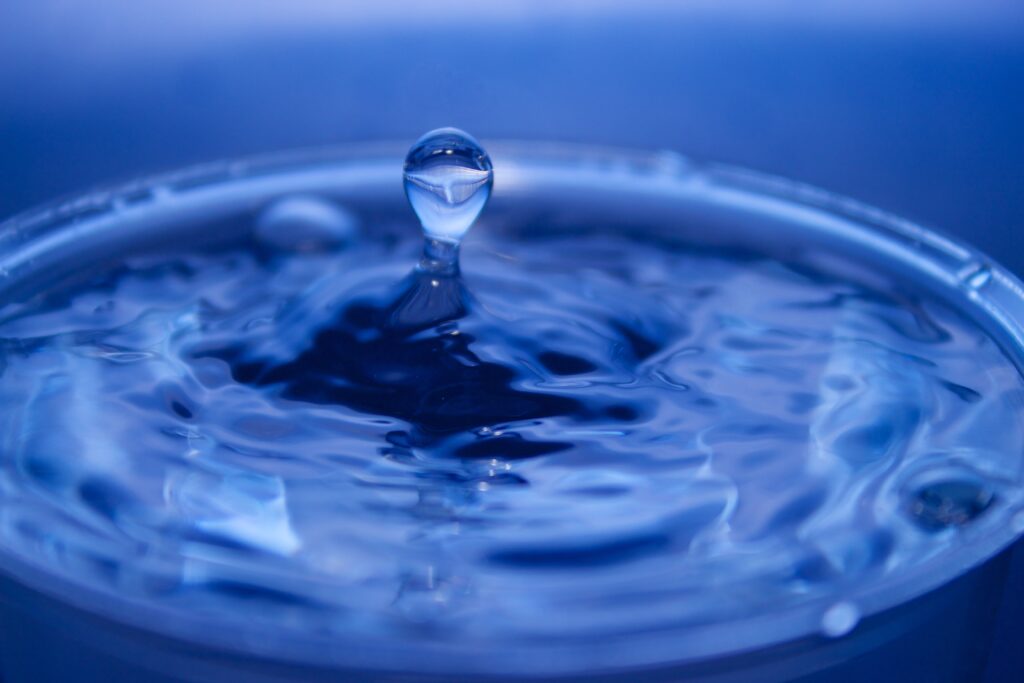 Serene Macro Wallpaper: Water Drop Ripples on Soothing Blue Background
