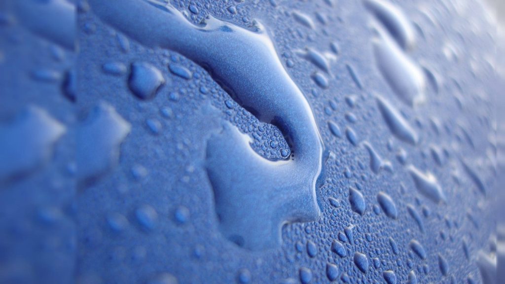 Macro photo of clear water droplets on textured blue surface with soft lighting desktop wallpaper