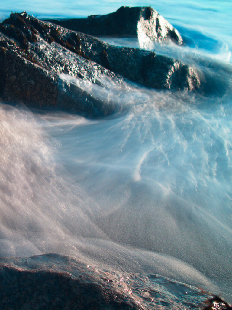 Serene macro flow of water over smooth stones and sand with soft blue hues wallpaper background