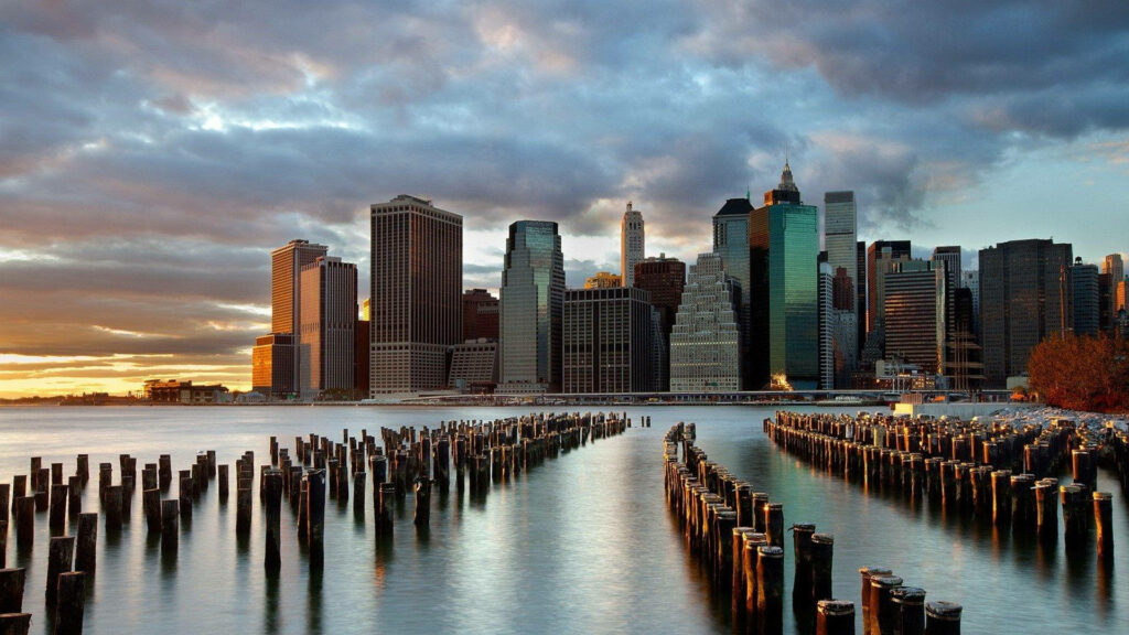 Serene Manhattan Sunset: Iconic Skyscrapers & Water Reflection Wallpaper