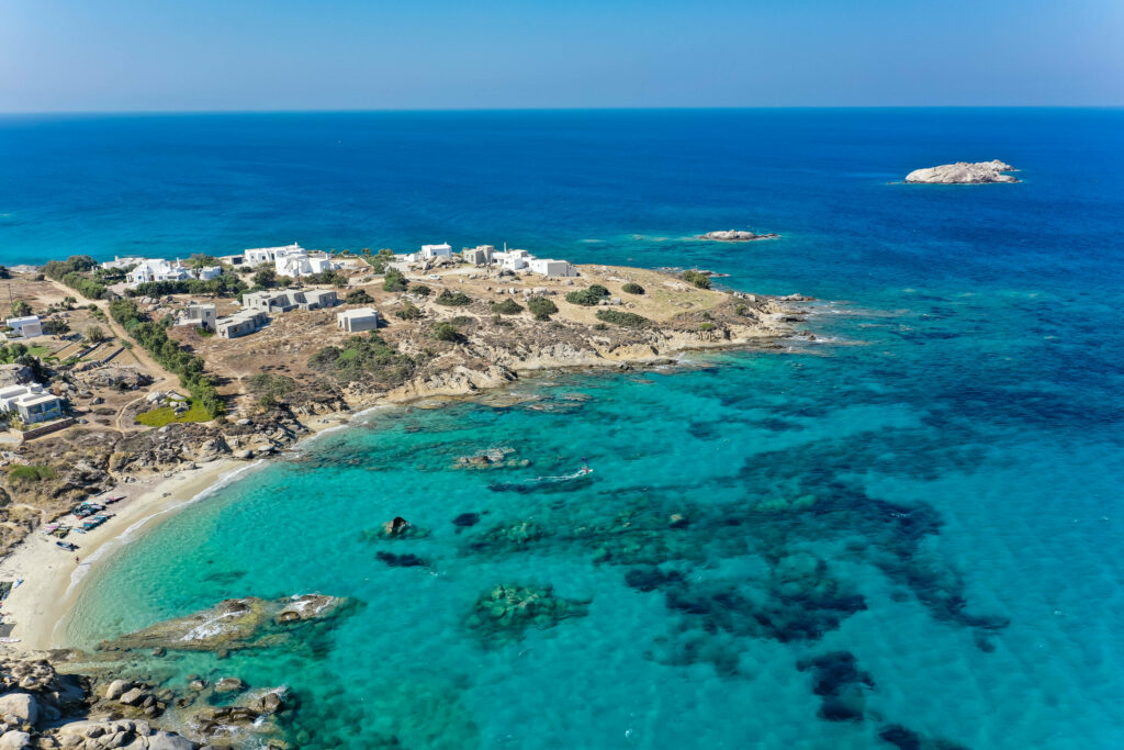 Serene Mediterranean island coast with turquoise sea white buildings and clear blue sky wallpaper