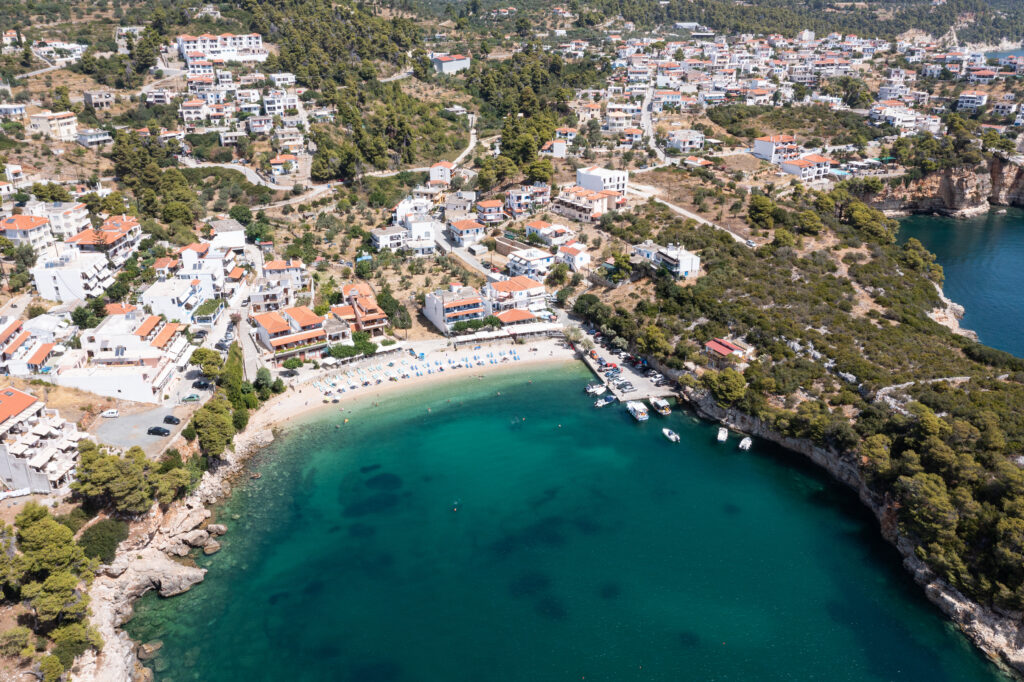 Aerial view of Mediterranean island town with white terracotta roofs green hillside beach and turquoise sea Wallpaper