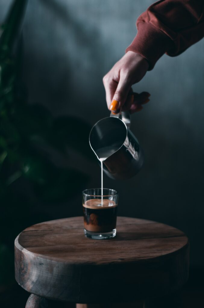 Serene Coffee Wallpaper: Hand Pouring Milk from Metal Pitcher