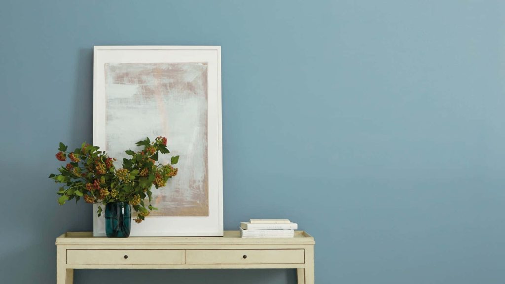 Serene minimalist Zoom background with muted blue wall console table abstract art and foliage Wallpaper